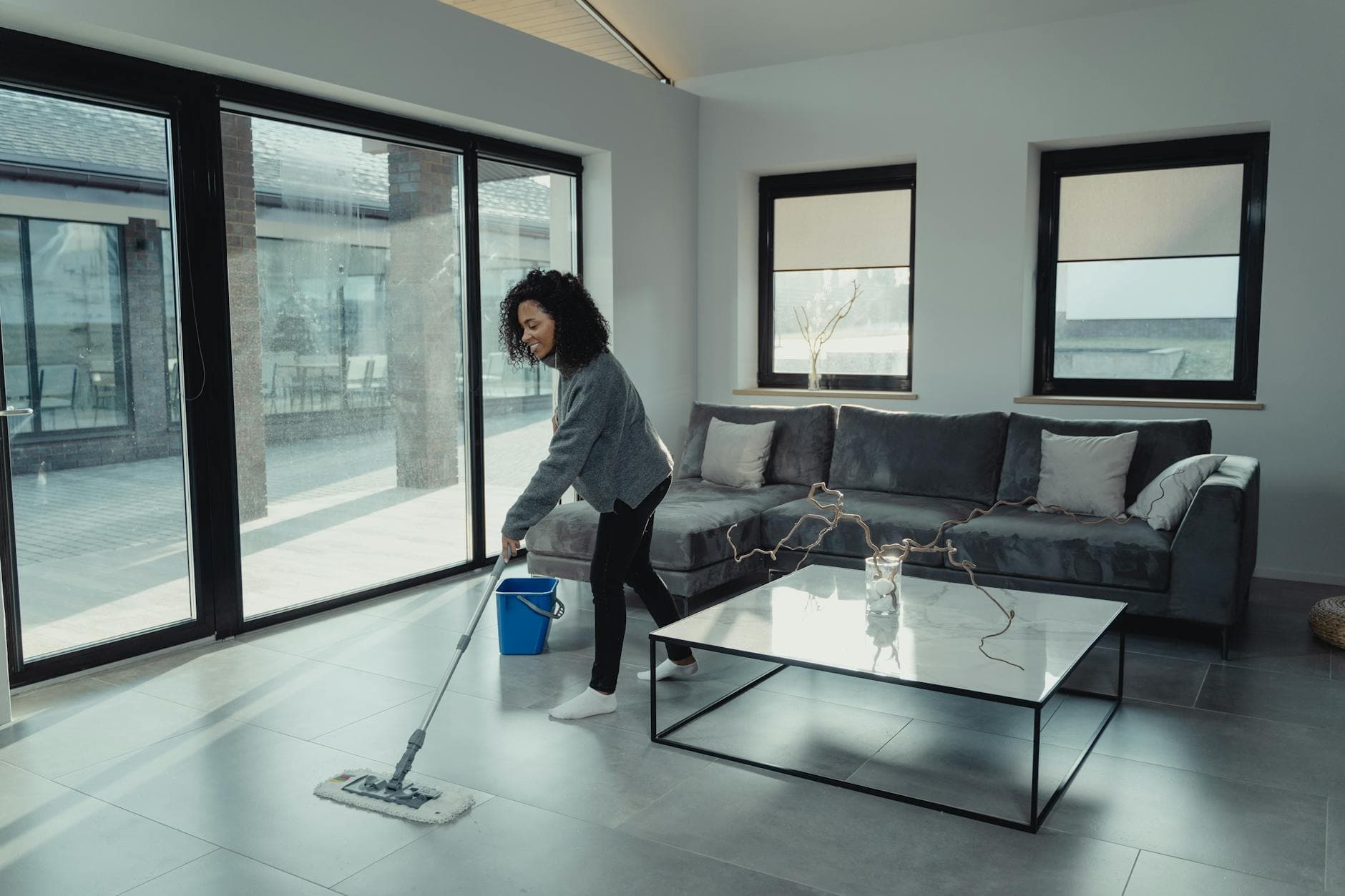 House cleaner mopping a bright, modern NYC apartment with large windows — cleaning services in Ocean Hill, Brooklyn