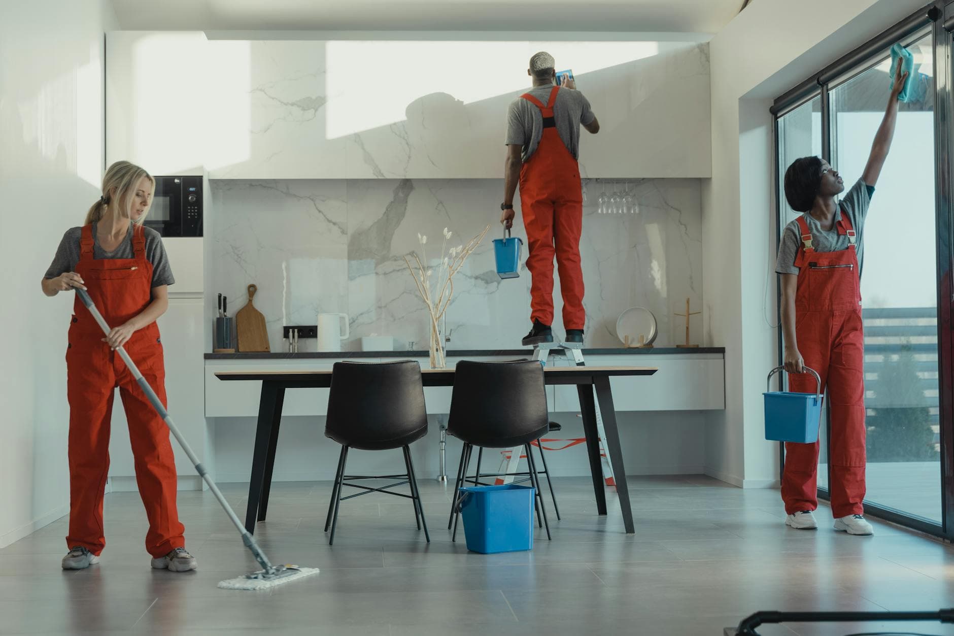 The NYC Maid cleaning crew in red uniforms mopping and wiping glass in a New York dining room — Office Cleaning in Stapleton, Staten Island