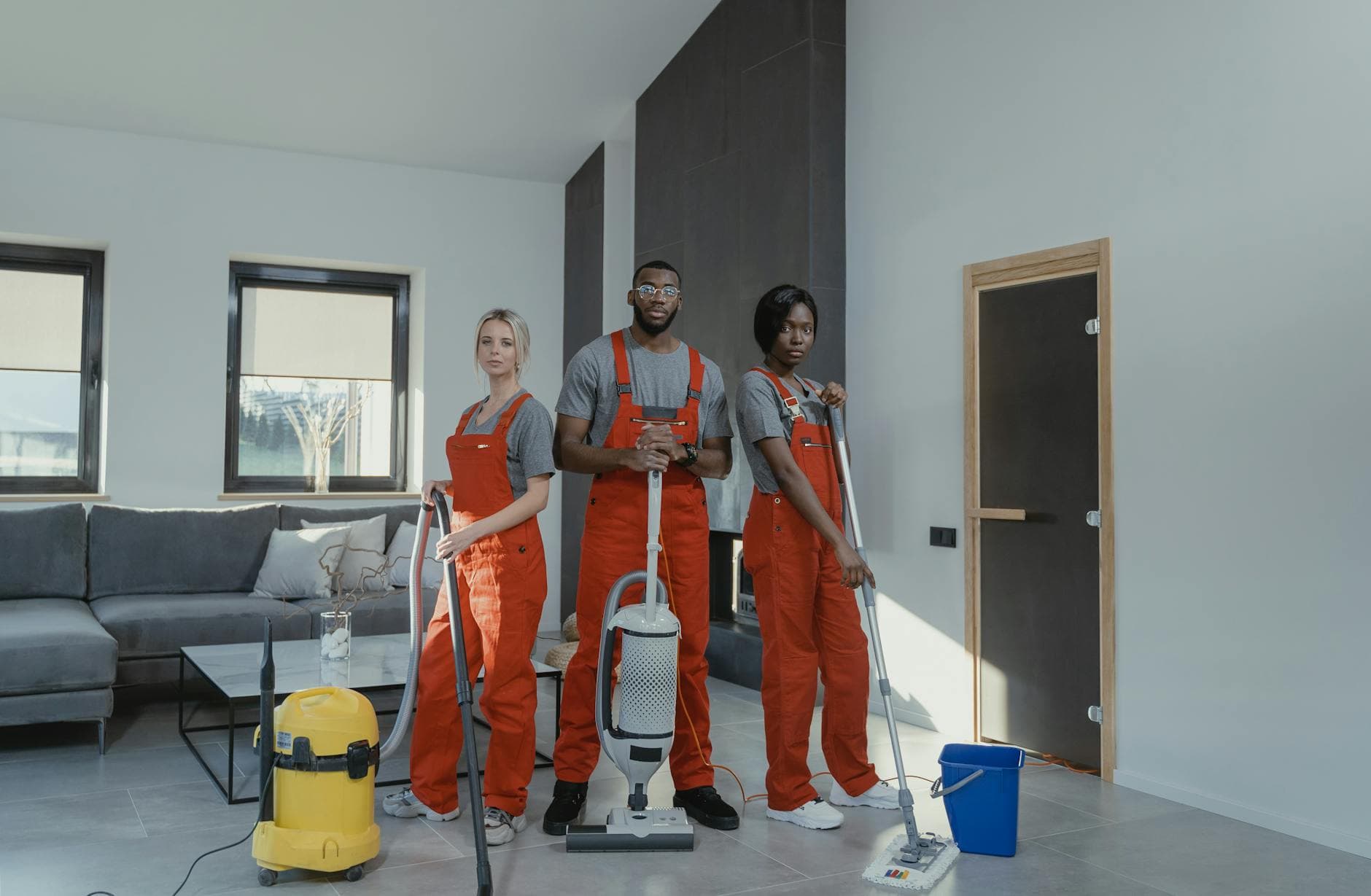 The NYC Maid cleaning team in red uniforms ready to sanitize a modern Manhattan living room — Office Cleaning in Peekskill, Westchester