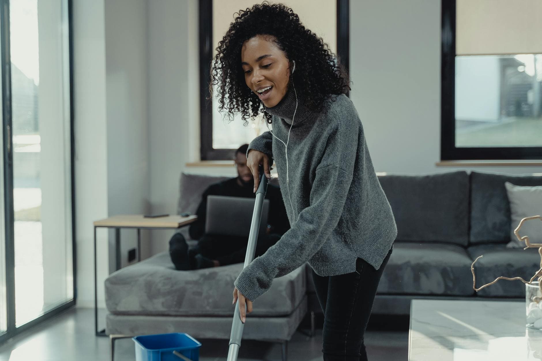 A professional house cleaner mopping the floor of a cozy New York City living room — Regular Apartment Cleaning in Ardsley, Westchester