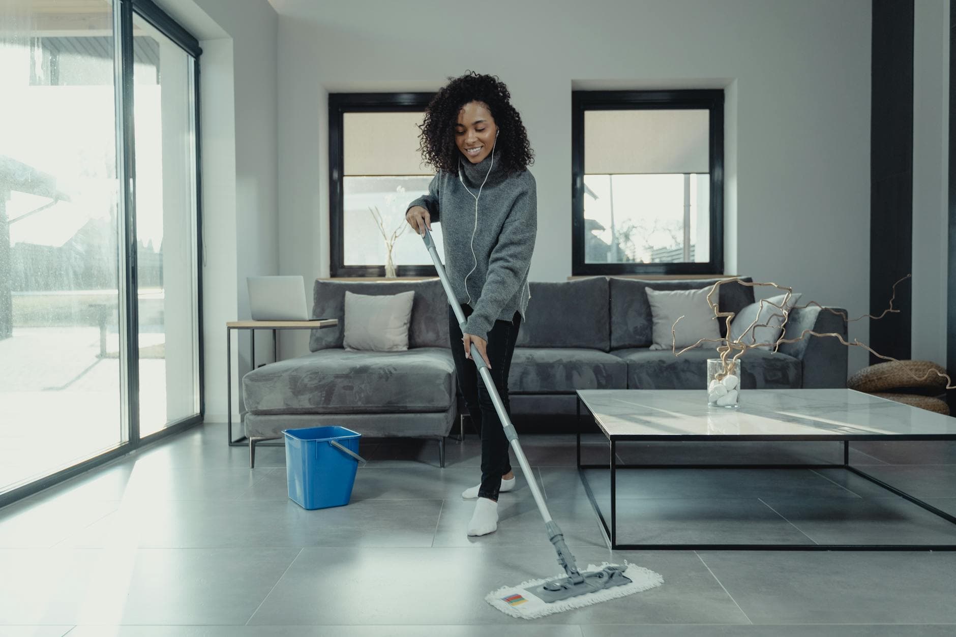 A maid from The NYC Maid mopping a tiled floor in a cozy New York City apartment — cleaning services in Syosset, Long Island