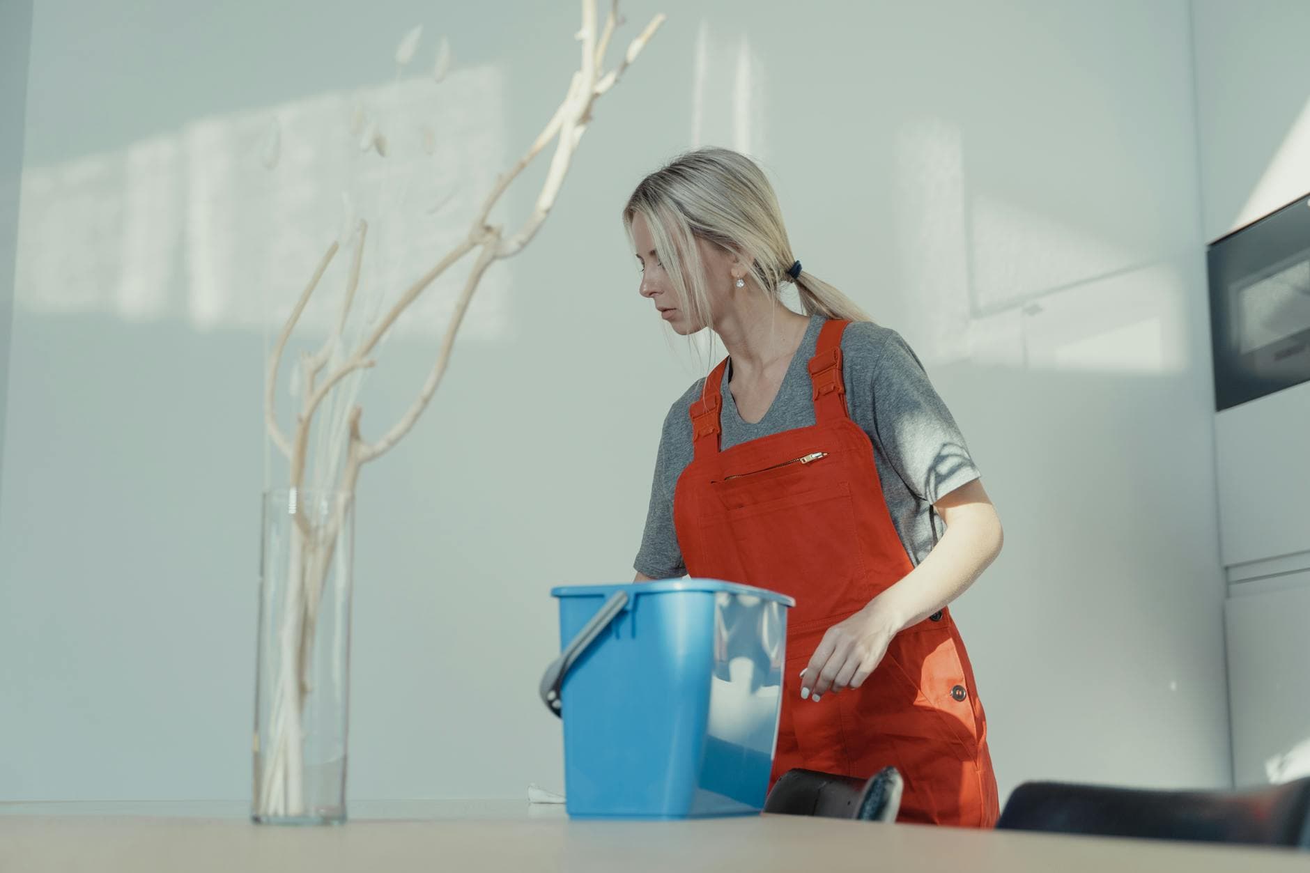 Professional cleaner from The NYC Maid in red uniform cleaning an NYC apartment with a bucket — Office Cleaning in Travis, Staten Island