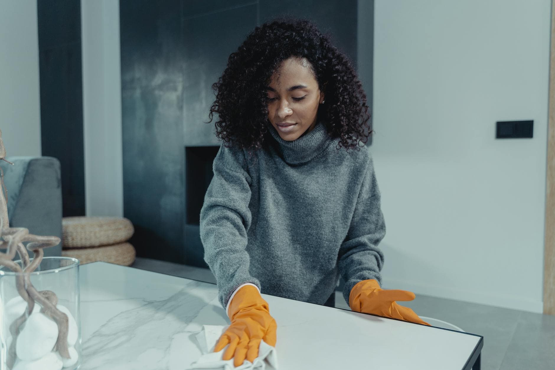 A NYC maid wearing gloves wiping a coffee table in a modern Manhattan living room — Bi-Weekly Cleaning in Upper West Side, Manhattan